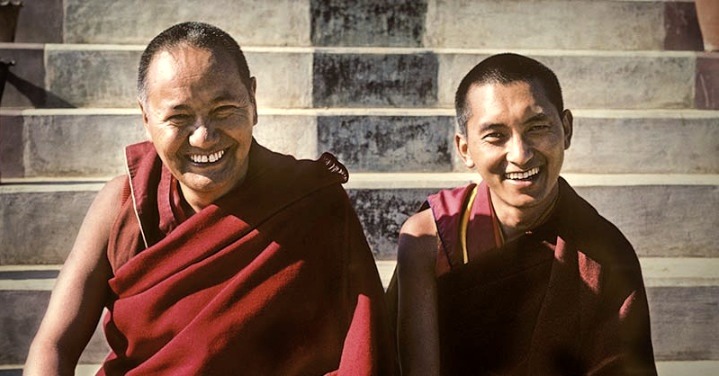 Lama Thubten Yeshe y Lama Zopa Rimpoché sonrientes, sentados en unas escaleras de piedra