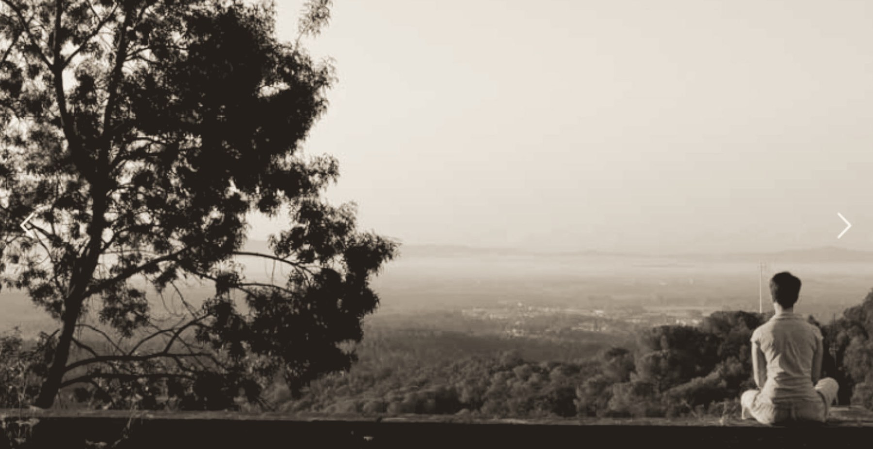 Persona sentada en meditación al aire libre frente a un paisaje de montaña al amanecer